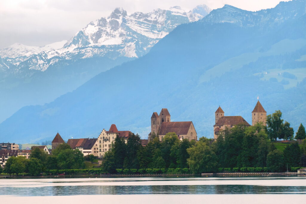 Image showing houses near a body of water and a mountainous background.